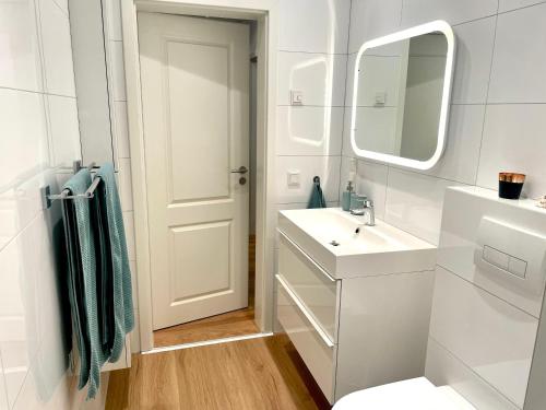 a white bathroom with a sink and a mirror at Gemütliche Ferienwohnung in Drolshagen