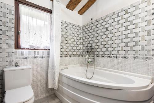 a white bathroom with a tub and a toilet at Casa Rural Adrimar in Selorio