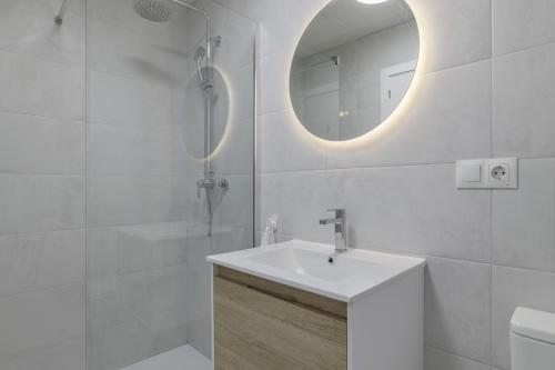 a white bathroom with a sink and a mirror at La Casa de Emilie- Solo Familias in Conil de la Frontera