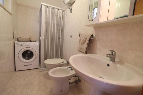 a bathroom with a sink and a toilet and a washing machine at Casa Vacanze Marta in Otranto