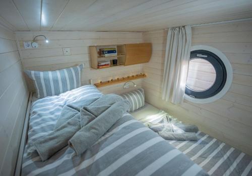 a small bedroom with a bed and a window at Magisches Abenteuer-Hausboot Juno in Fürstenberg