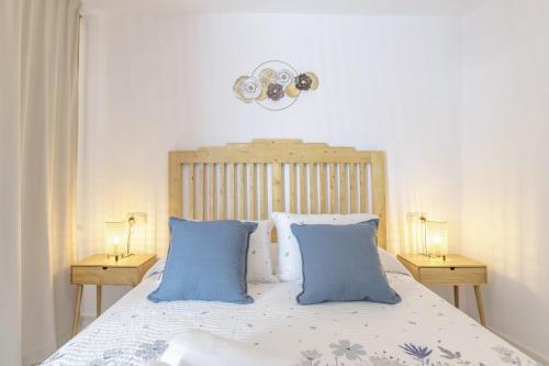 a bedroom with a bed with blue pillows and two lamps at El Rincón de Hugo in Alcalá de los Gazules