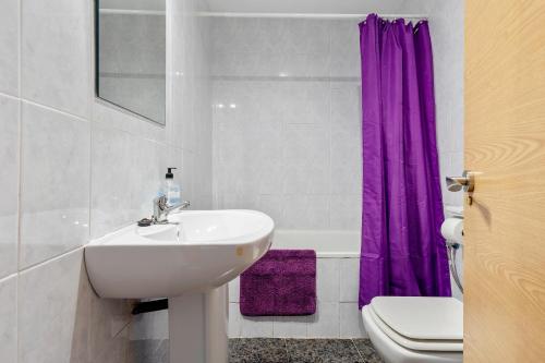 a bathroom with a sink and a purple shower curtain at Masía Costa Daurada in Tarragona
