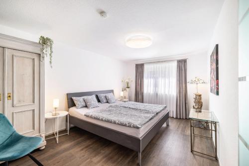 a white bedroom with a bed and a window at Die Schneiderei in Balingen