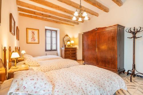 a bedroom with two beds and a wooden cabinet at Ca l'Andorrà in Vila-Sana