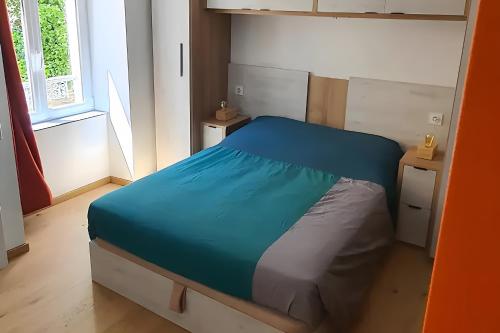 a bedroom with a blue bed in a room with a window at Appartement La Perle Du Sancy in La Bourboule