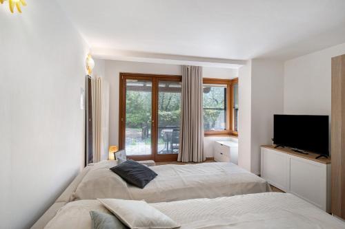 a bedroom with two beds and a tv and a window at Il Giardino del Sole, Chalet Salvia in Garlenda
