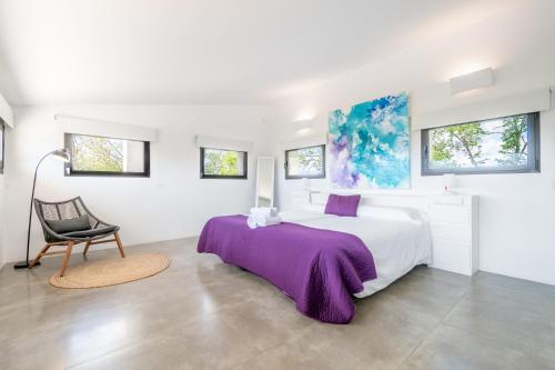 a white bedroom with a large bed and a chair at Dalt Son Morro in Santa Margalida