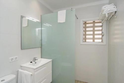 a white bathroom with a sink and a mirror at Anglesos in Can Picafort