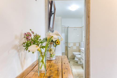 a vase of flowers on a wooden table in front of a mirror at Villetta La Pajara in Morciano di Leuca