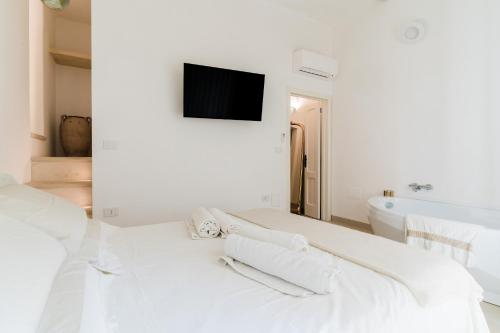 a white bedroom with a bed and a tv on a wall at Bacchus Historic Home in Otranto