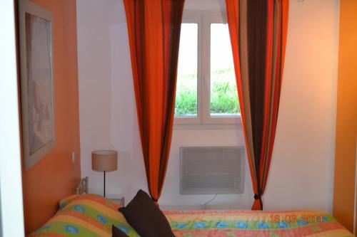 a bedroom with a bed and a window with curtains at Rez-de-villa Taglio-Isolaccio in Taglio-Isolaccio