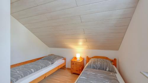 a bedroom with two beds and a night stand at Waldblick - Stilvolles Ferienhaus in Kemmerode