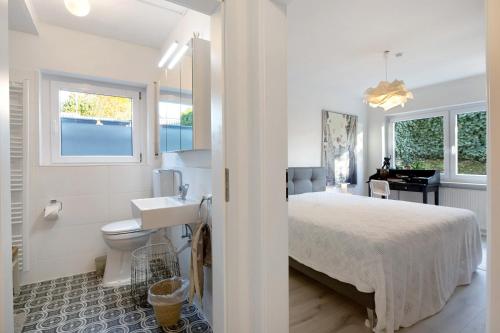 a white bedroom with a bed and a sink at Apartment Dreiländer Blick in Wintersweiler