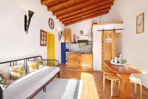 a living room with a bench and a table and a kitchen at Quinta do Mestre - Casa do Campo in Tavira