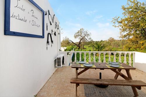 a wooden picnic table on a balcony with a sign at Quinta do Mestre - Casa do Campo in Tavira