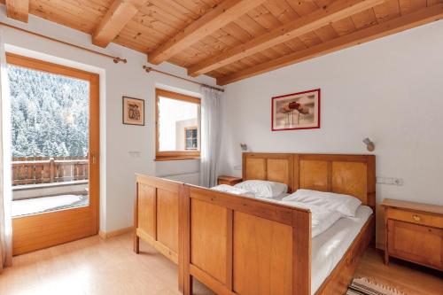 a bedroom with a wooden bed and a window at Heinzenhof Welschnofen in Nova Levante