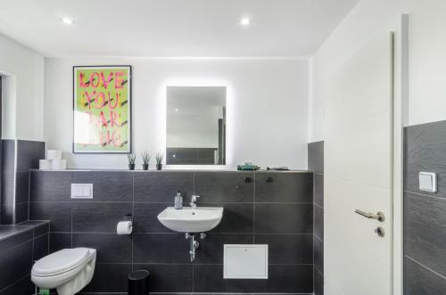 a bathroom with a sink and a toilet and a mirror at Moin, die Ferienwohnung in Wilhelmshaven