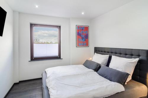 a bedroom with a bed and a window at Moin, die Ferienwohnung in Wilhelmshaven