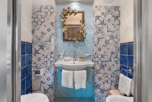 a blue tiled bathroom with a sink and a mirror at Romantico casale di lusso con Spa in Conca dei Marini