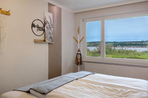 a bedroom with a bed and a large window at Seeluft direkt am Wasser in Reichenau