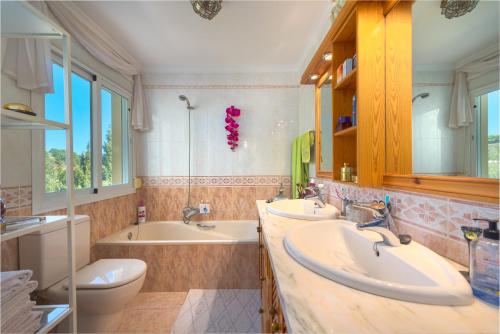 a bathroom with two sinks and a tub and a toilet at Villa Roca Penthouse in Estepona