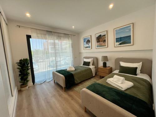 a bedroom with two beds and a large window at The Olive Tree Apartment in Tavira