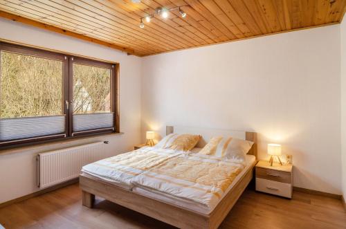 a bedroom with a large bed and two windows at Fewo Jaeger in Bad Sachsa