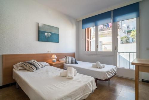 two beds in a room with a window at Canet Beach 1 in Canet de Mar