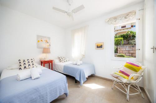 a bedroom with two beds and a chair and a window at Can Botana 7 in Cala de Sant Vicenc