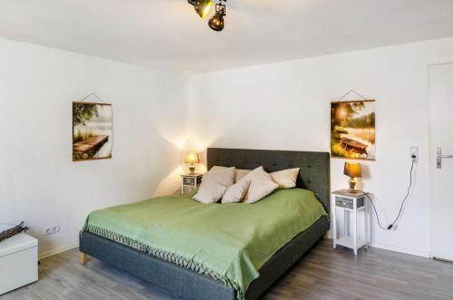 a bedroom with a green bed with two lamps at Ferienwohnung am Vogler in Holenberg