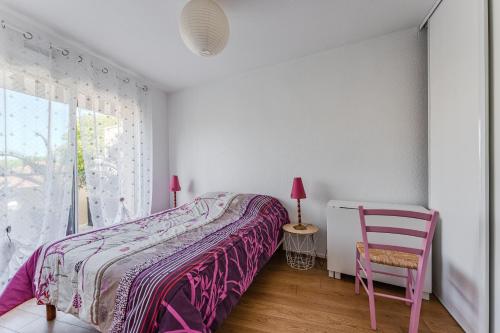 Un dormitorio con una cama y una silla rosa. en Petitbuch, en La Teste-de-Buch