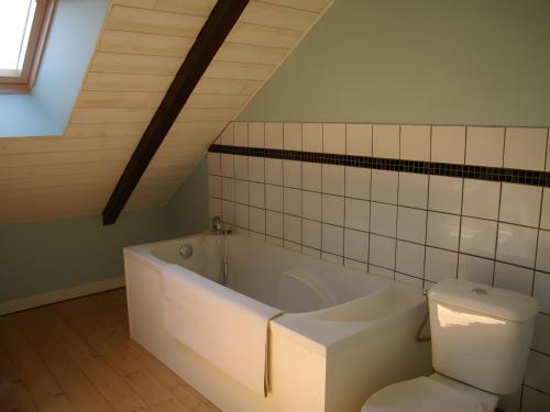 a bathroom with a white tub and a toilet at Gîte Joly in Corseul