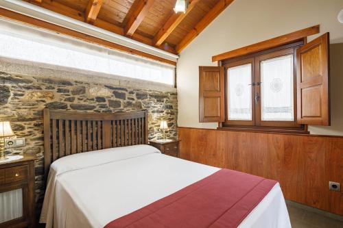 a bedroom with a bed and a stone wall at Camiño in Ordes