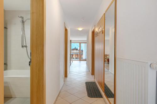 a hallway with a bathroom with a tub and a shower at Residence Nussbaumer in Siusi