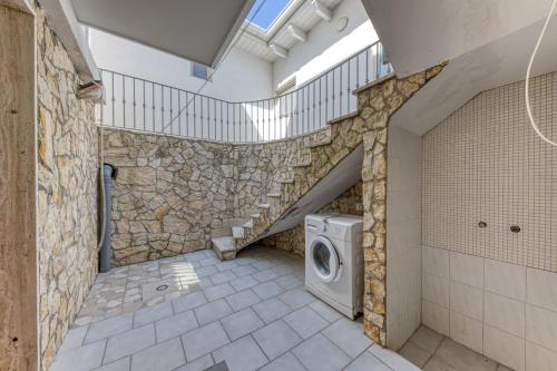 a bathroom with a washing machine in a stone wall at Pilella in Alliste