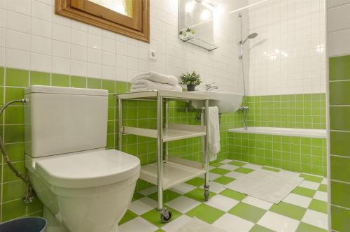 a green and white bathroom with a toilet and a sink at Vistas a Moraira in Teulada