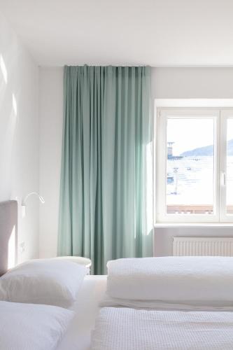 a white bedroom with two beds and a window at Hus Appartement - Nr. 4 in Valdaora