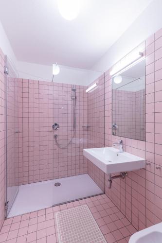 a pink tiled bathroom with a sink and a shower at Hus Appartement - Nr. 4 in Valdaora