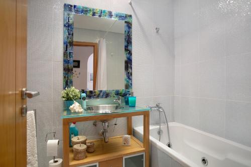 a bathroom with a sink and a tub and a mirror at Praia Areia Branca in Lourinhã