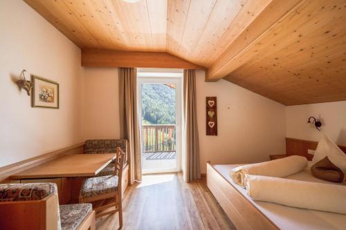 a room with a bed and a table and a window at Sonnleiten der kleinen Bären 9 in Collepietra