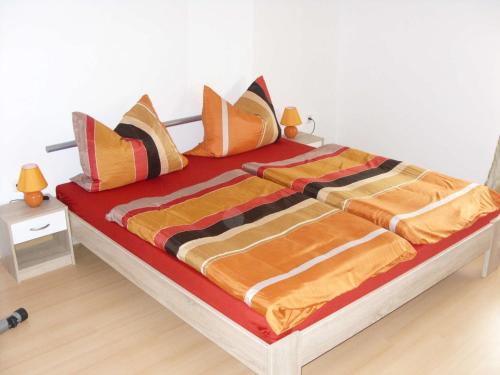 a large bed with orange and orange sheets and pillows at Ferienwohnung Schopper in Halblech