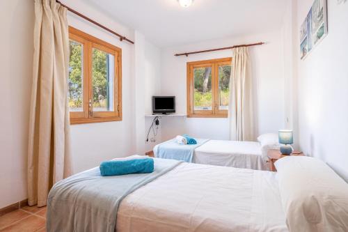 two beds in a white room with two windows at Santa Eulalia in Can Picafort
