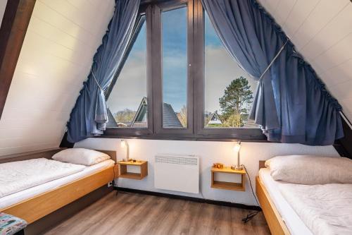 two beds in a room with two windows at Sonnenschein Am Meer in Butjadingen