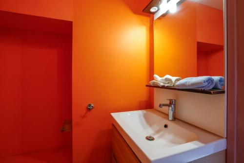 ein orangefarbenes Badezimmer mit Waschbecken und Spiegel in der Unterkunft Gite l'hermine in Cast