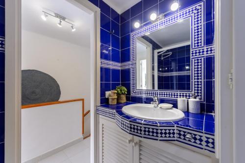 a blue tiled bathroom with a sink and a mirror at Casita en Cala Llonga in Cala Llonga