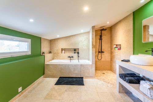 a bathroom with a white tub and green walls at Lila Mas in Camaret-sur-Aigues