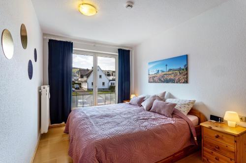 a bedroom with a bed and a large window at Fewo Willingenliebe Meinecardplus in Willingen