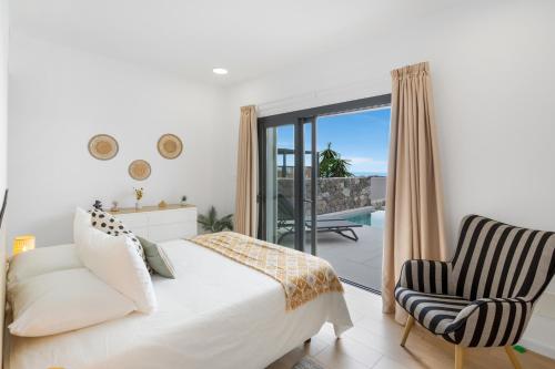 a bedroom with a bed and a chair and a balcony at Yucas Villa 14 in San Bartolomé