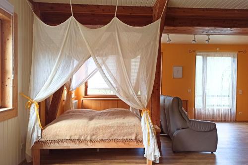 a bedroom with a canopy bed and a chair at Bahnhof Durlesbach in Bad Waldsee